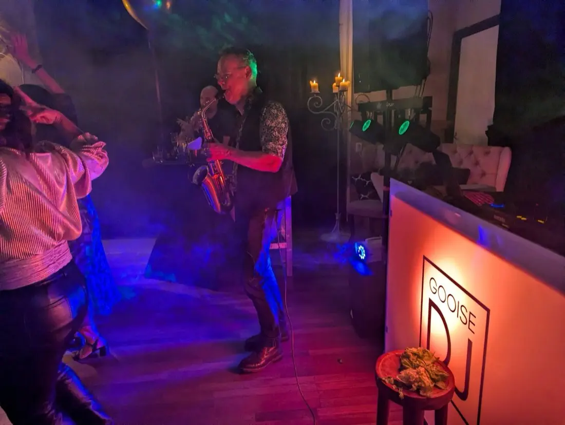Saxofonist Peter speelt naast de DJ-set van de Gooise DJ, met dansende gasten, rook en gekleurd licht